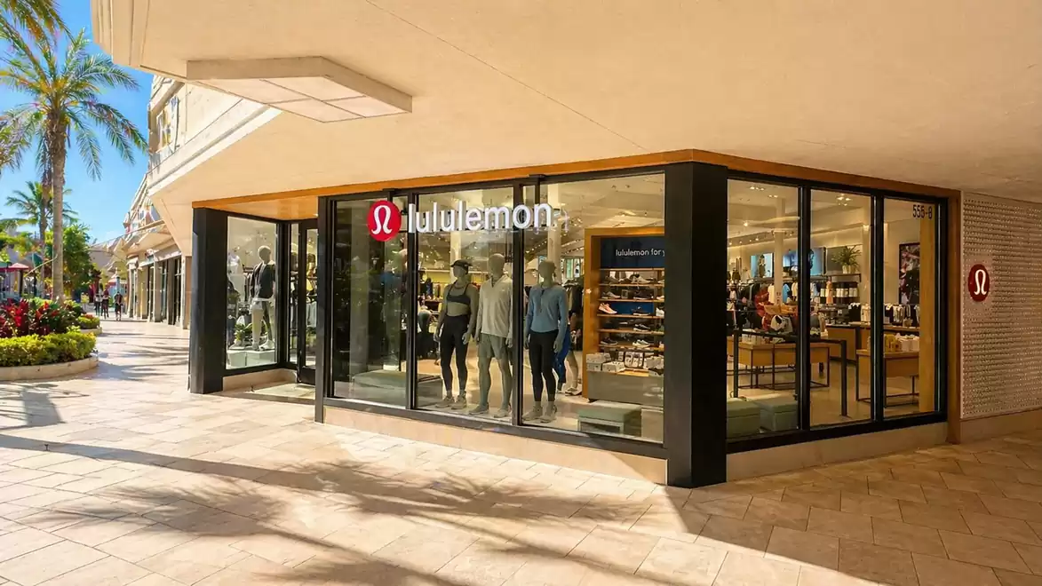 Lululemon storefront with mannequins and clothing displays in a shopping center on a sunny day.