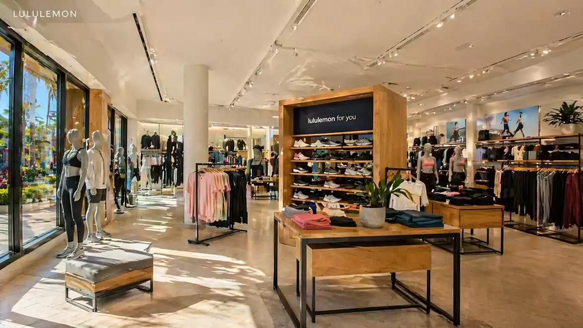 A modern, bright sportswear store with shelves full of clothing and accessories, along with mannequins.