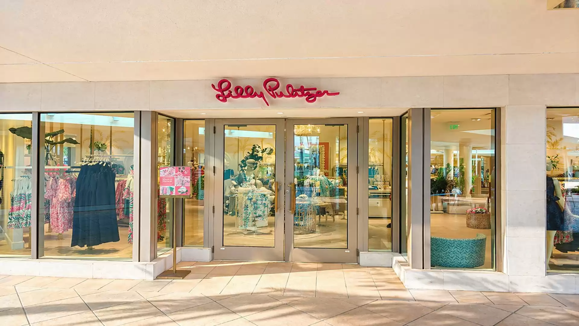 Inviting view of a fashion store with large glass fronts and a red sign above the entrance door.