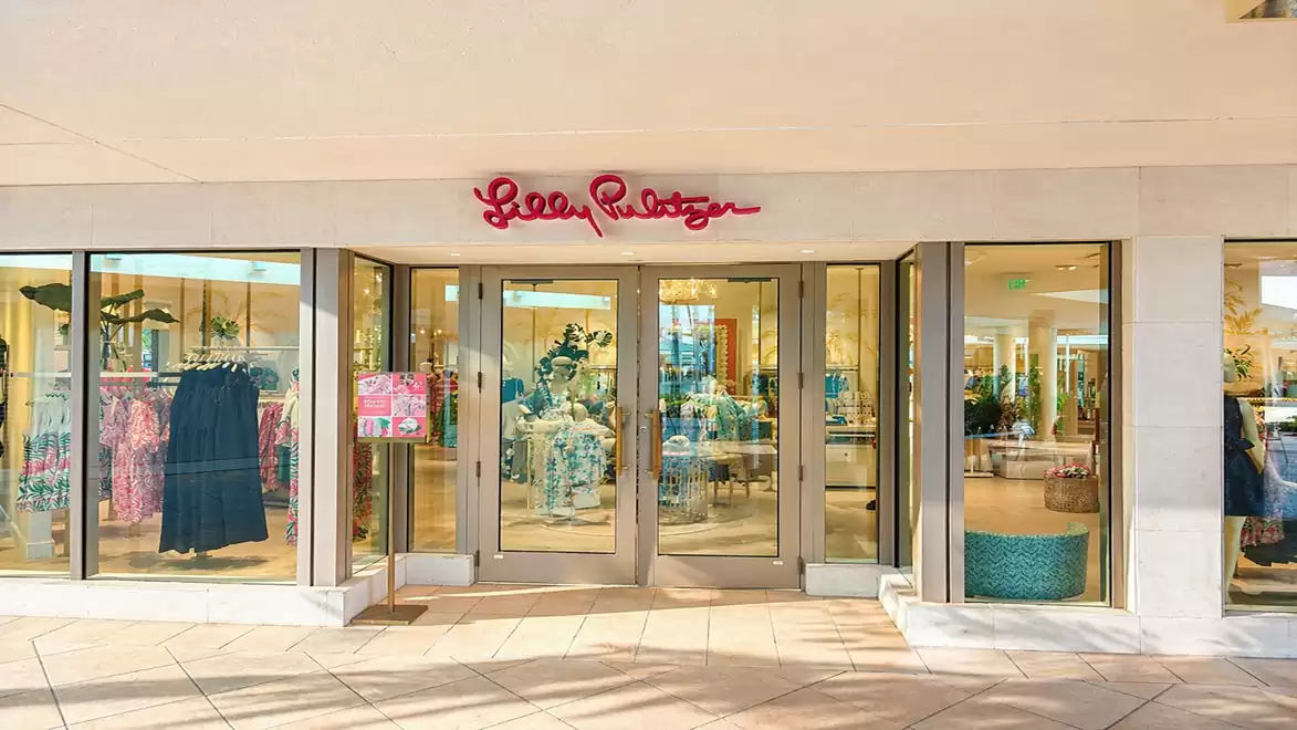 Inviting view of a fashion store with large glass fronts and a red sign above the entrance door.