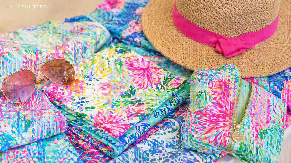 Summer fashion accessories with a hat, sunglasses, and colorful fabrics in tropical colors.