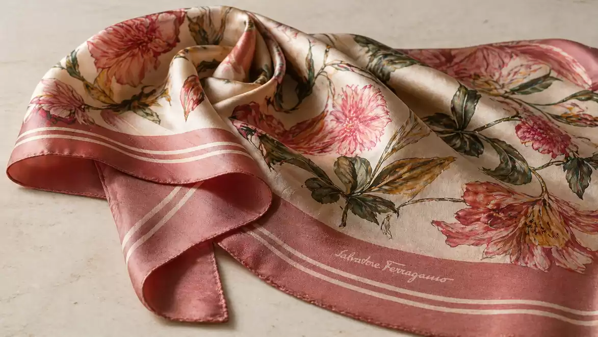 Silk scarf with floral patterns draped on a table.