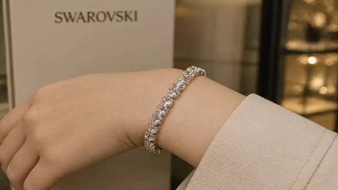Elegant Swarovski bracelet on a wrist in front of Swarovski packaging.