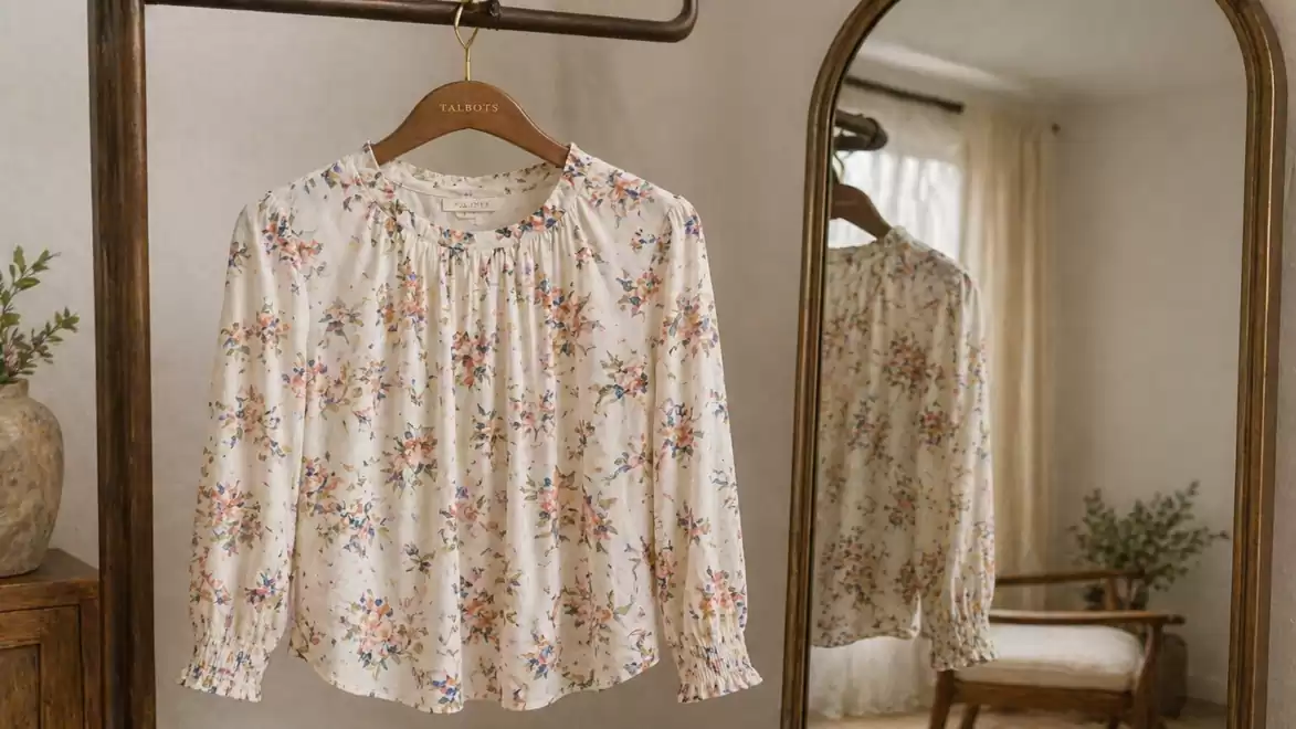 Floral blouse on a hanger in front of a mirror in a stylishly furnished room.