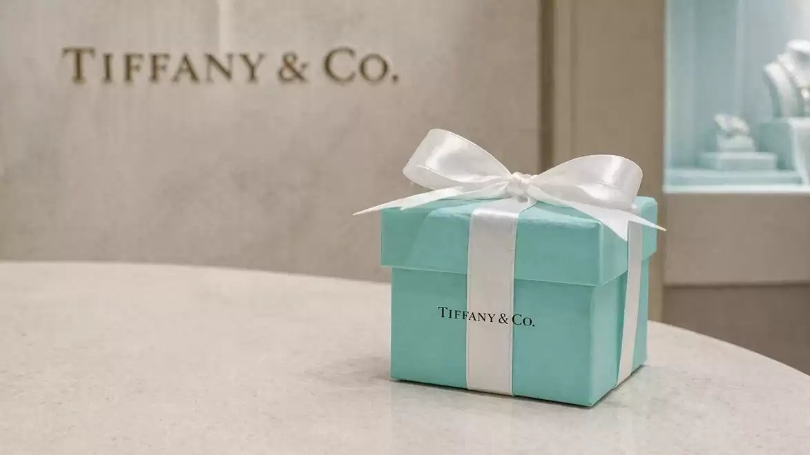 A Tiffany & Co. gift box with a white ribbon, on a table in a store.