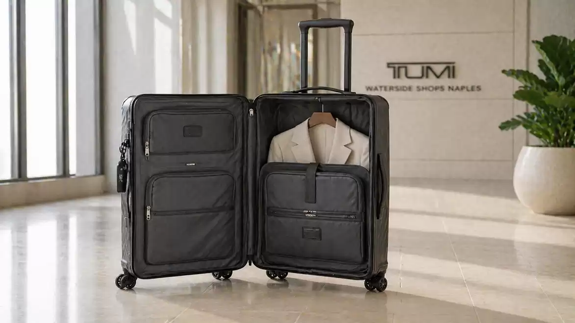 An open black suitcase in a modern room with natural light. The suitcase reveals an organized interior containing a light-colored suit.