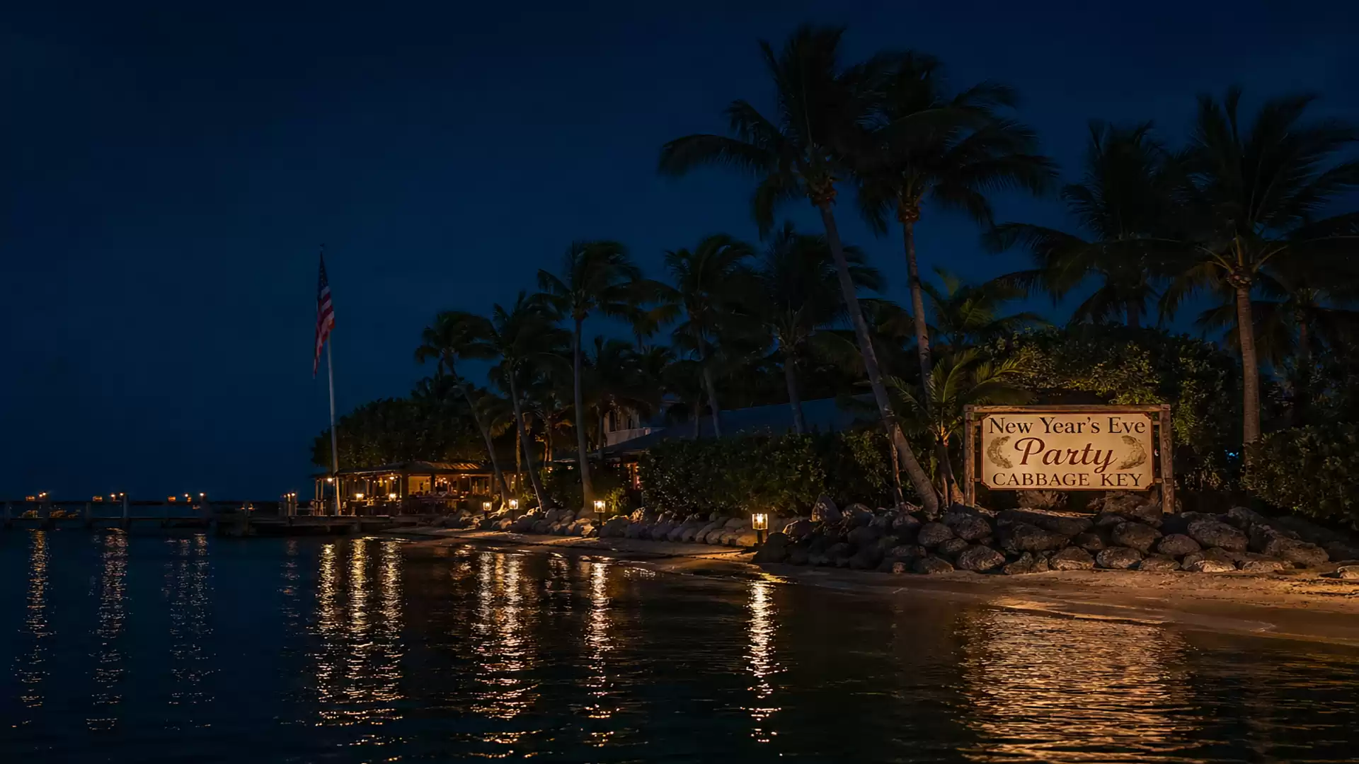 A nighttime beach scene with palm trees, illuminated by warm lights and a sign inviting to a New Year's Eve party.