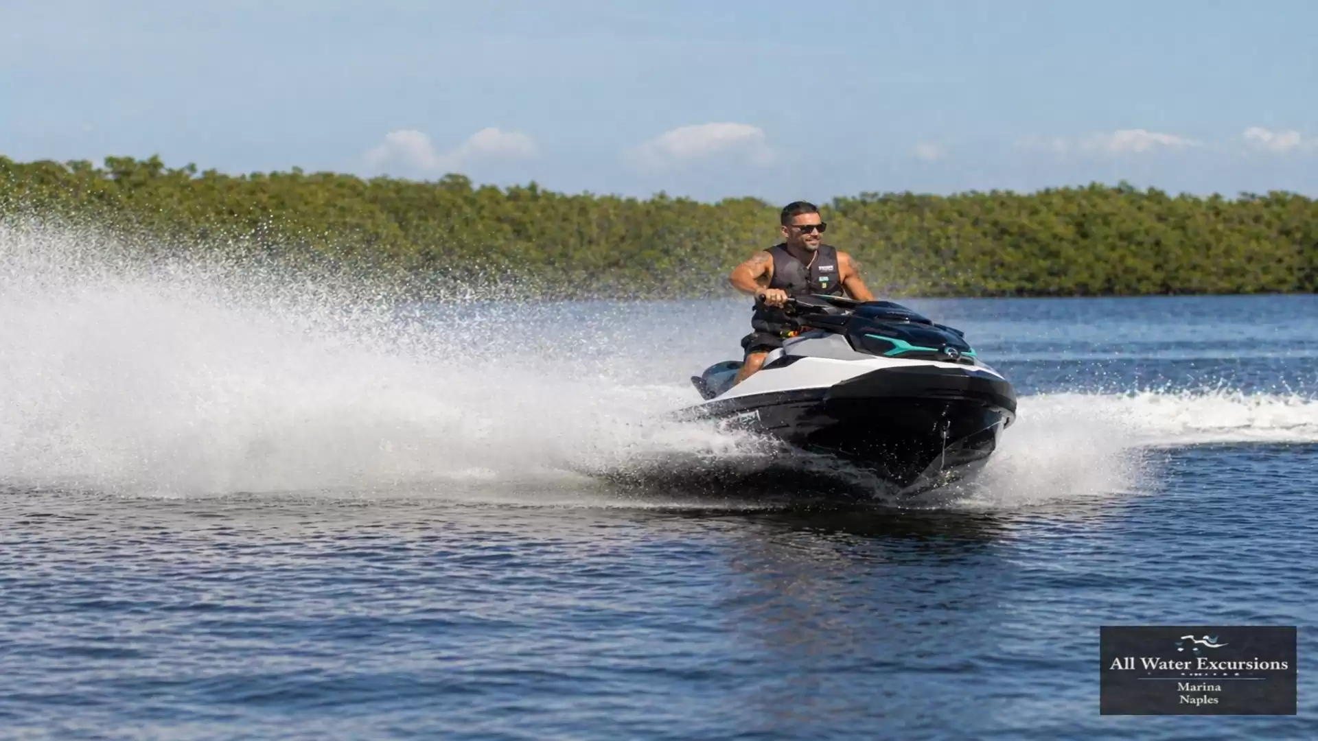 Person riding a jet ski on the water under sunny skies, leaving a trail of spray behind.