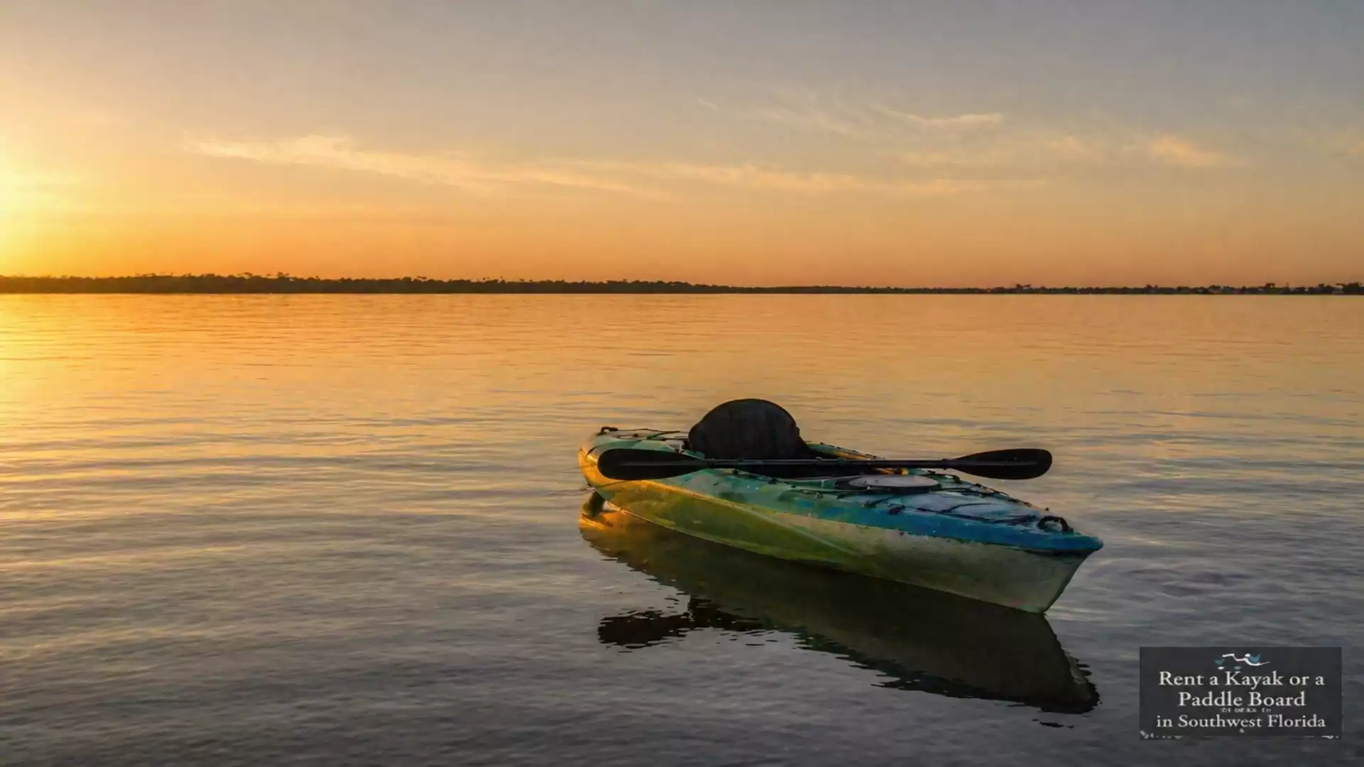 A single kayak floats on a calm lake at sunset.