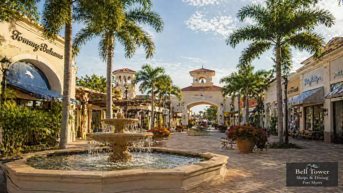 Spanish-style shopping street with palm trees and a large fountain in the center.