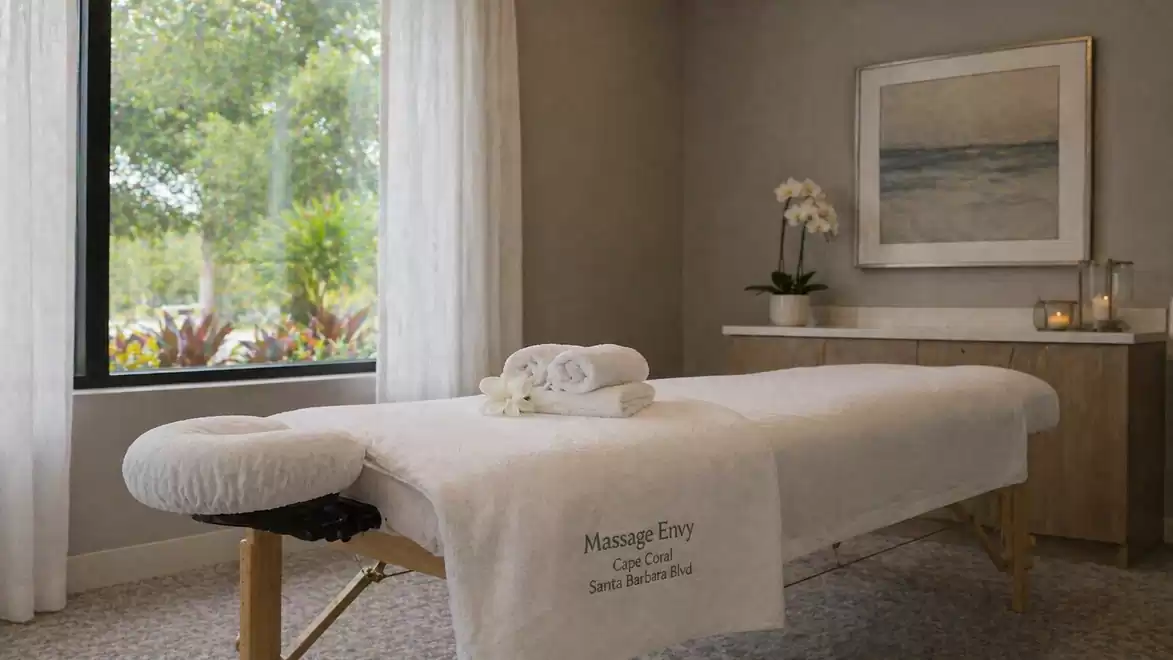 An elegant massage room with a padded table, a plant, and calming lighting.