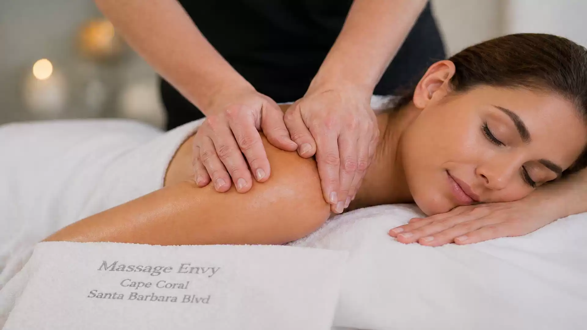 Woman relaxing during a professional massage in a spa room with a white towel.