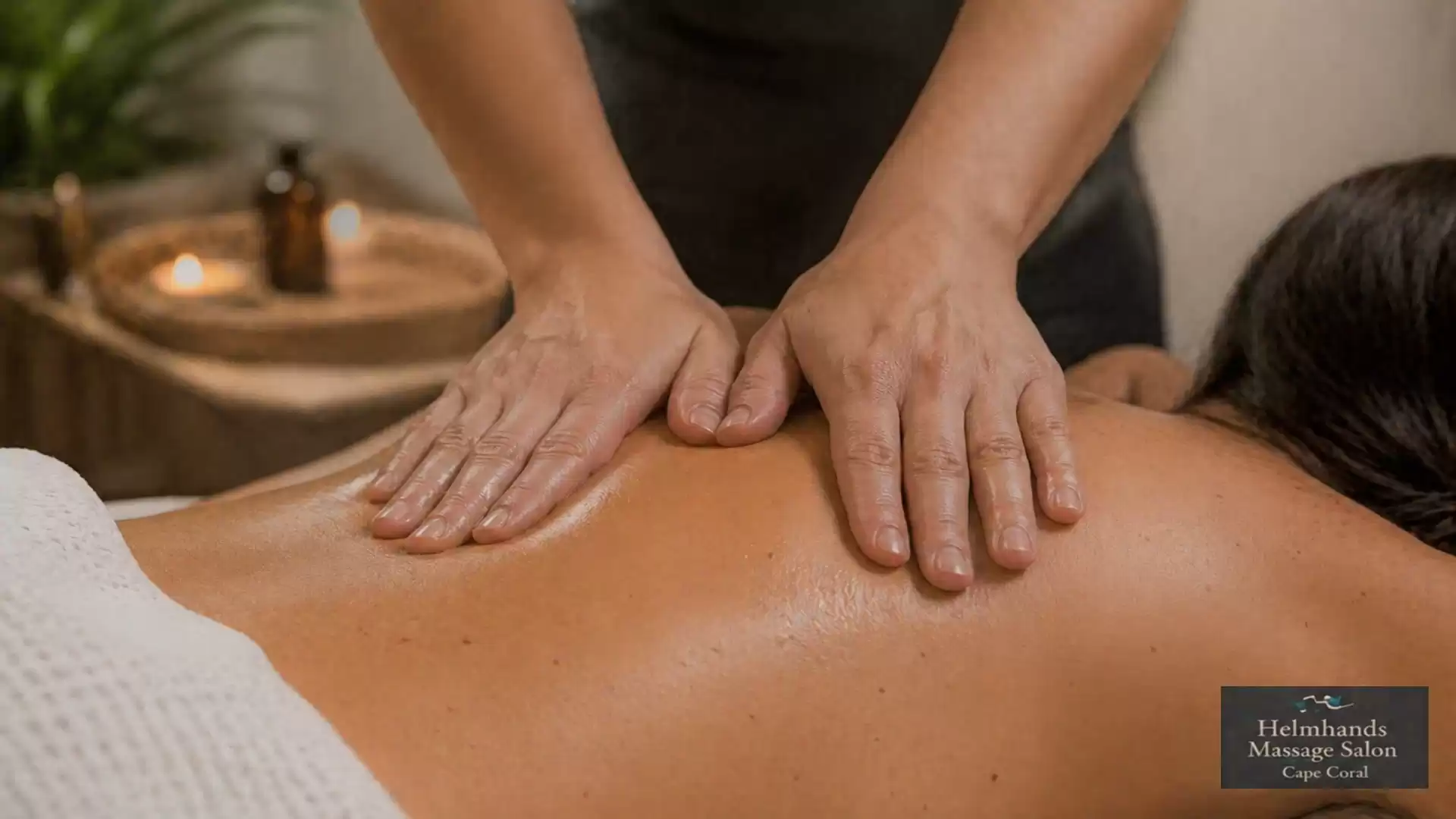 Close-up of a professional massage with hands massaging a person's back in a relaxing atmosphere with candlelight.