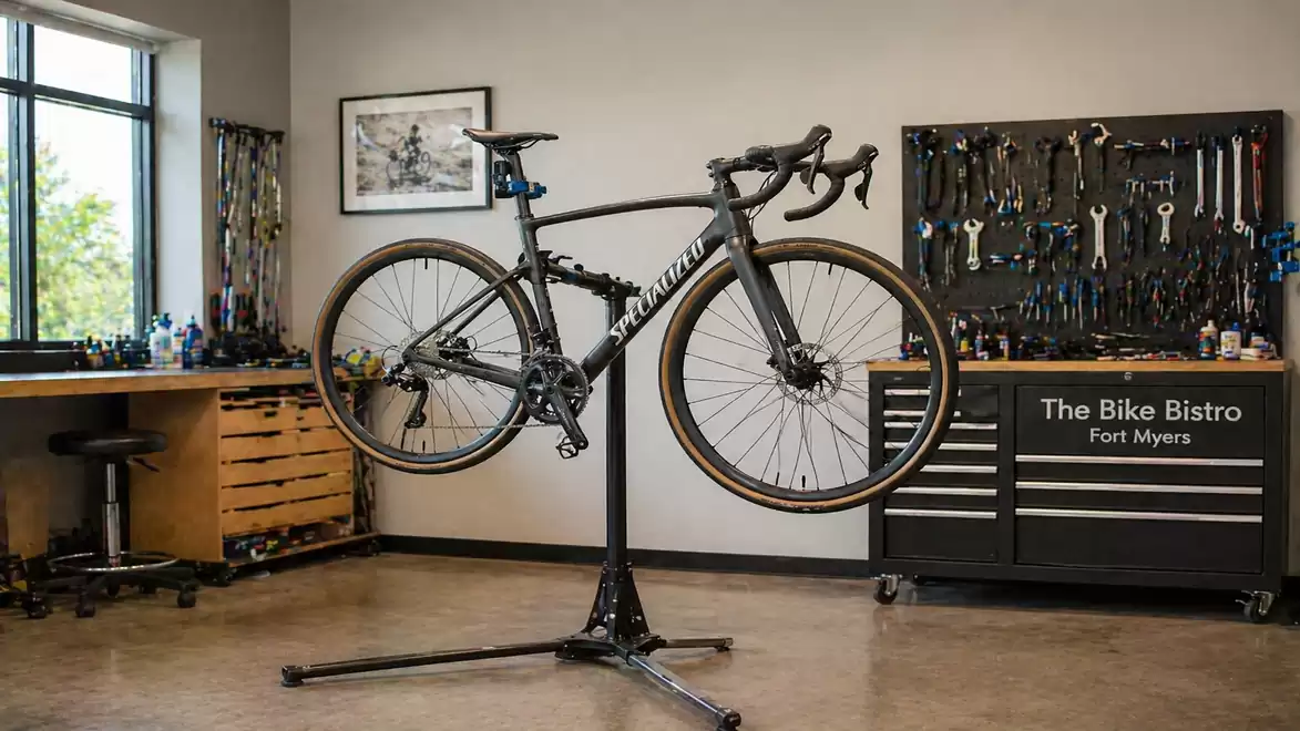 Interior view of a bike workshop with a bicycle on a stand surrounded by tools and workbenches.