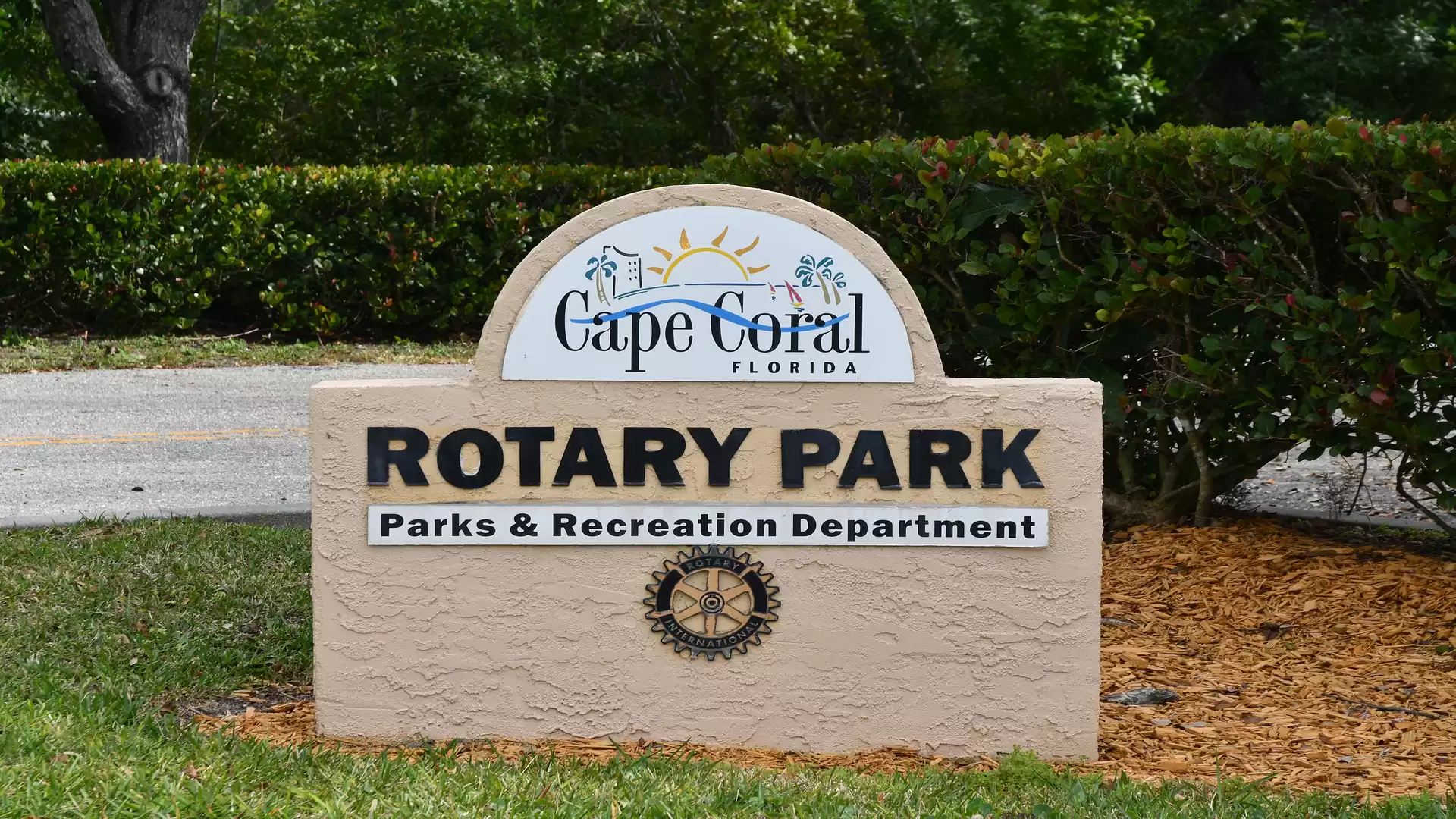 A stone monument at Rotary Park in Cape Coral, Florida, with the inscription 'Rotary Park Parks & Recreation Department'. Surrounded by green vegetation.