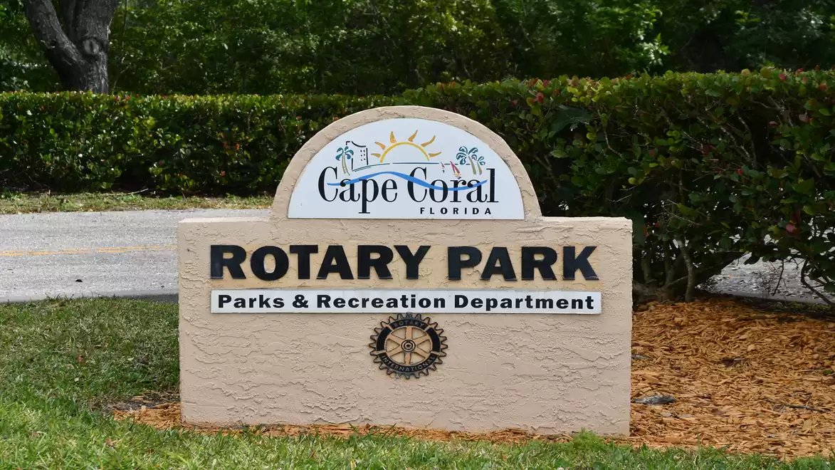 A stone monument at Rotary Park in Cape Coral, Florida, with the inscription 'Rotary Park Parks & Recreation Department'. Surrounded by green vegetation.