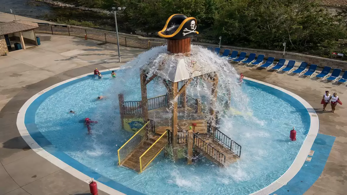 Pirate-themed water park with a splash pad and large pirate hat in a round pool.