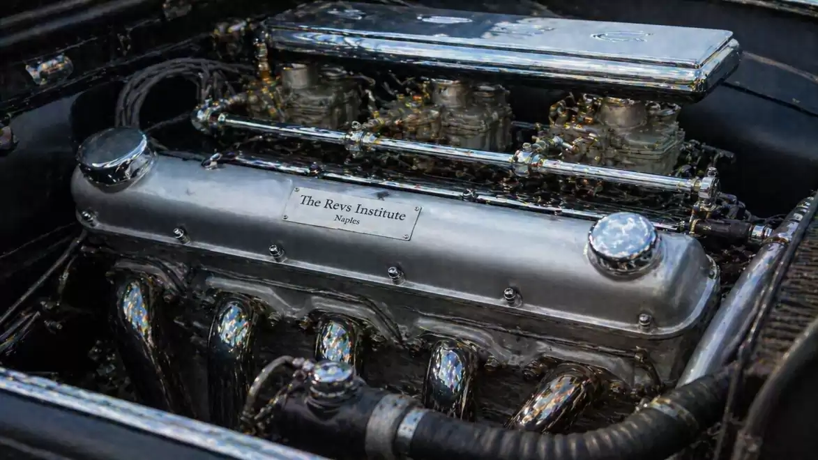 Close-up of a classic car engine with detailed metallic components and piping.
