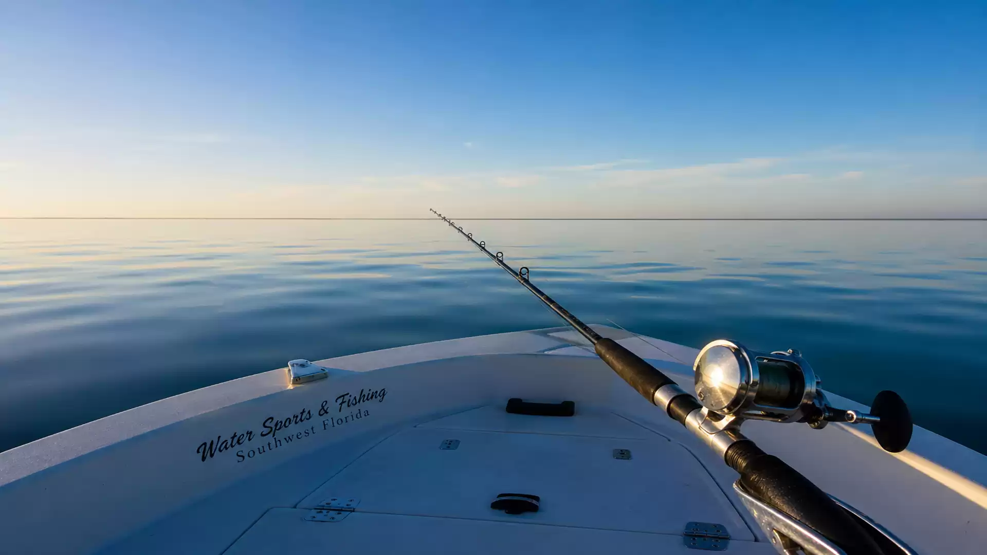 Fishing rod on a boat with calm sea and blue sky.