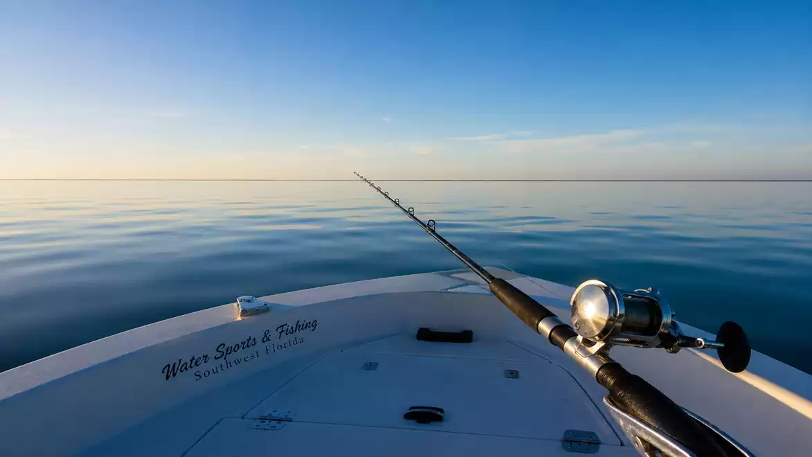 Fishing rod on a boat with calm sea and blue sky.
