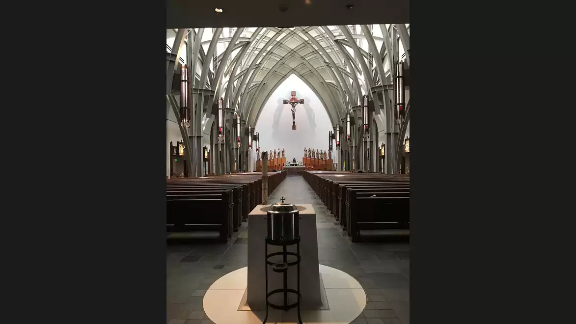 Interior of a modern church with wooden benches and a large cross above the altar.
