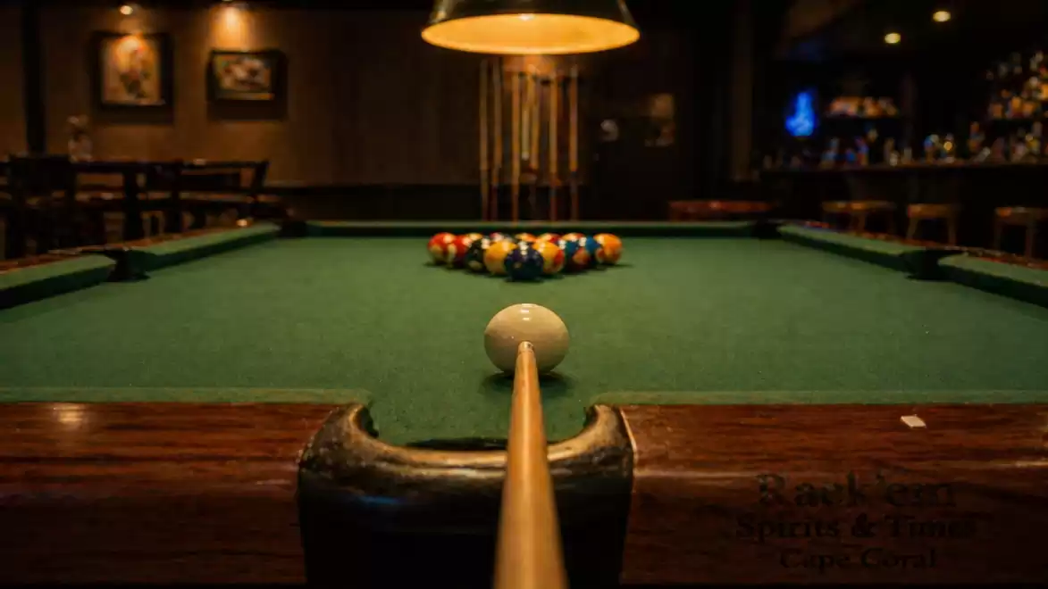 View of a pool table in a stylish bar with balls arranged for the game.