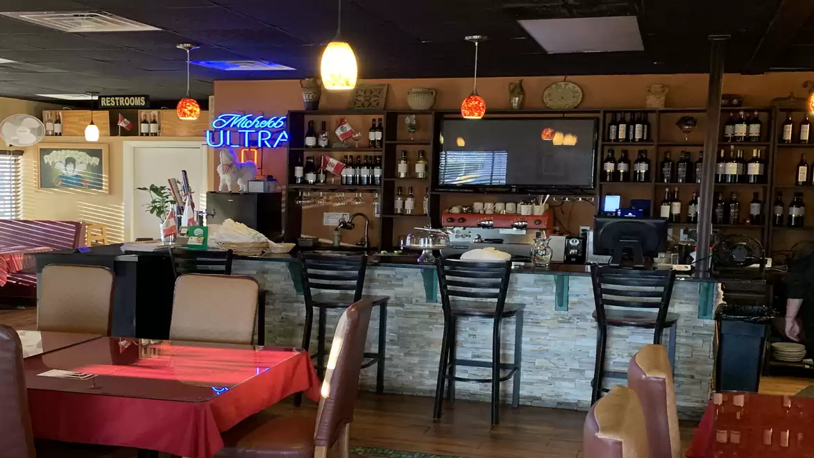 Cozy bar with wooden decor, a well-stocked counter, and several seating areas in the foreground.