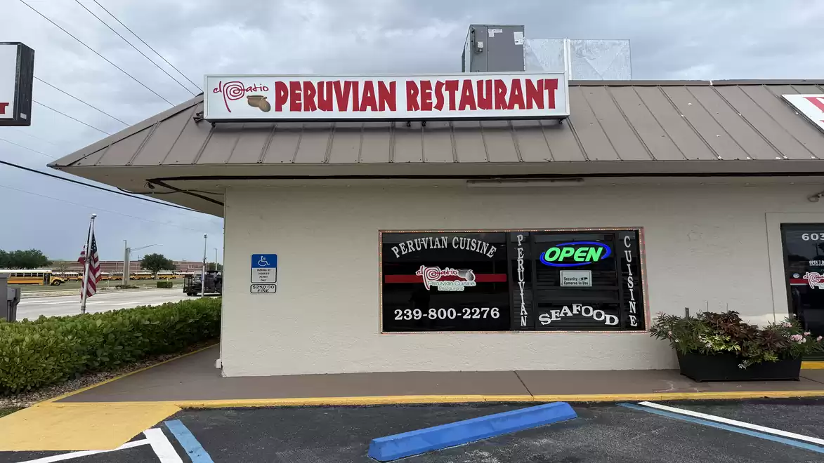 Exterior view of a Peruvian restaurant with a large sign above the entrance. The restaurant displays signs for Peruvian cuisine and seafood, with an open sign and phone number.