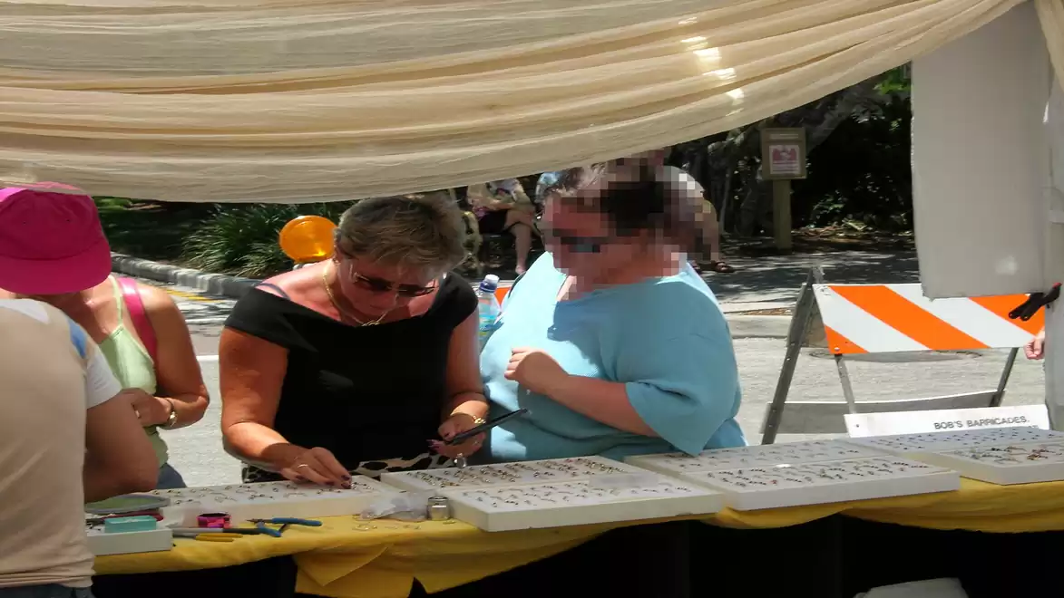 People at a market stall in sunny weather.