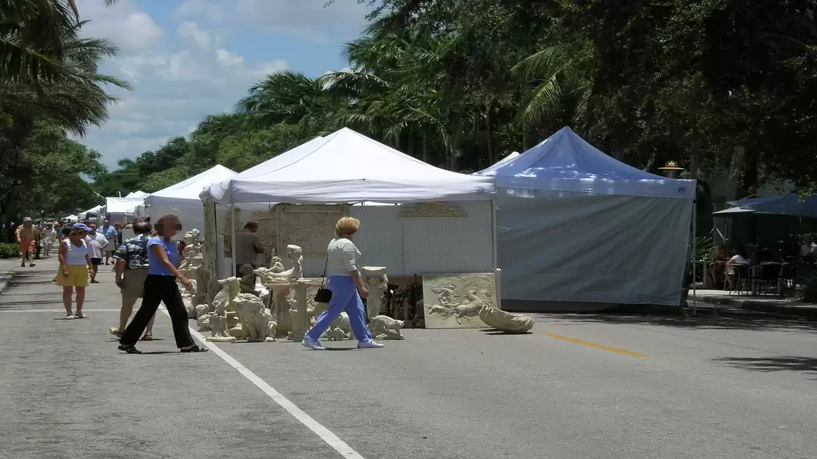 Street market with white tents and pedestrians on a sunny day.