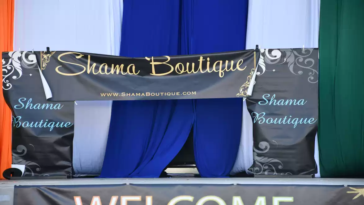 A boutique stall decorated with a stylish banner and colored curtains, displaying the name 'Shama Boutique'.