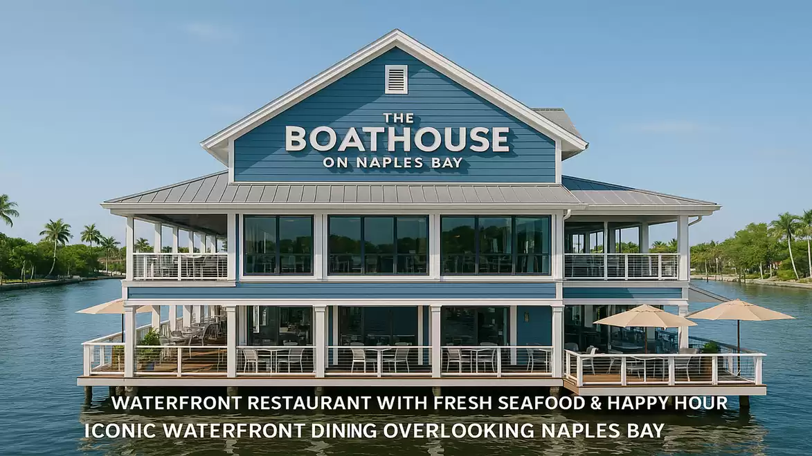 A blue, traditionally designed restaurant named 'The Boathouse on Naples Bay' is located by the water, surrounded by palm trees and a clear sky. It offers waterfront dining and fresh seafood.