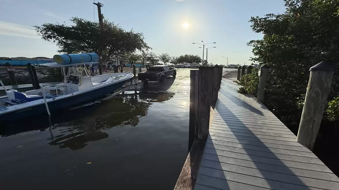 A serene harbor with docked boats and a wooden pier at sunset.