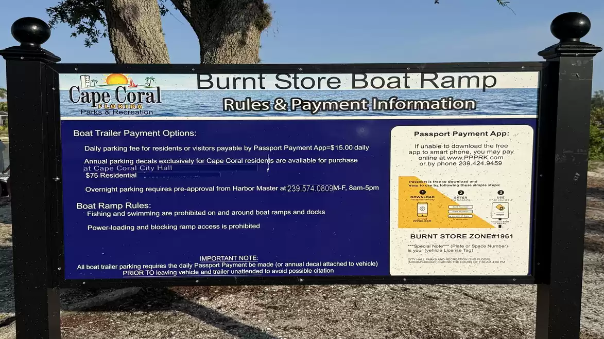 A sign at Burnt Store Boat Ramp in Cape Coral with rules and payment information for boat trailers and parking booking.