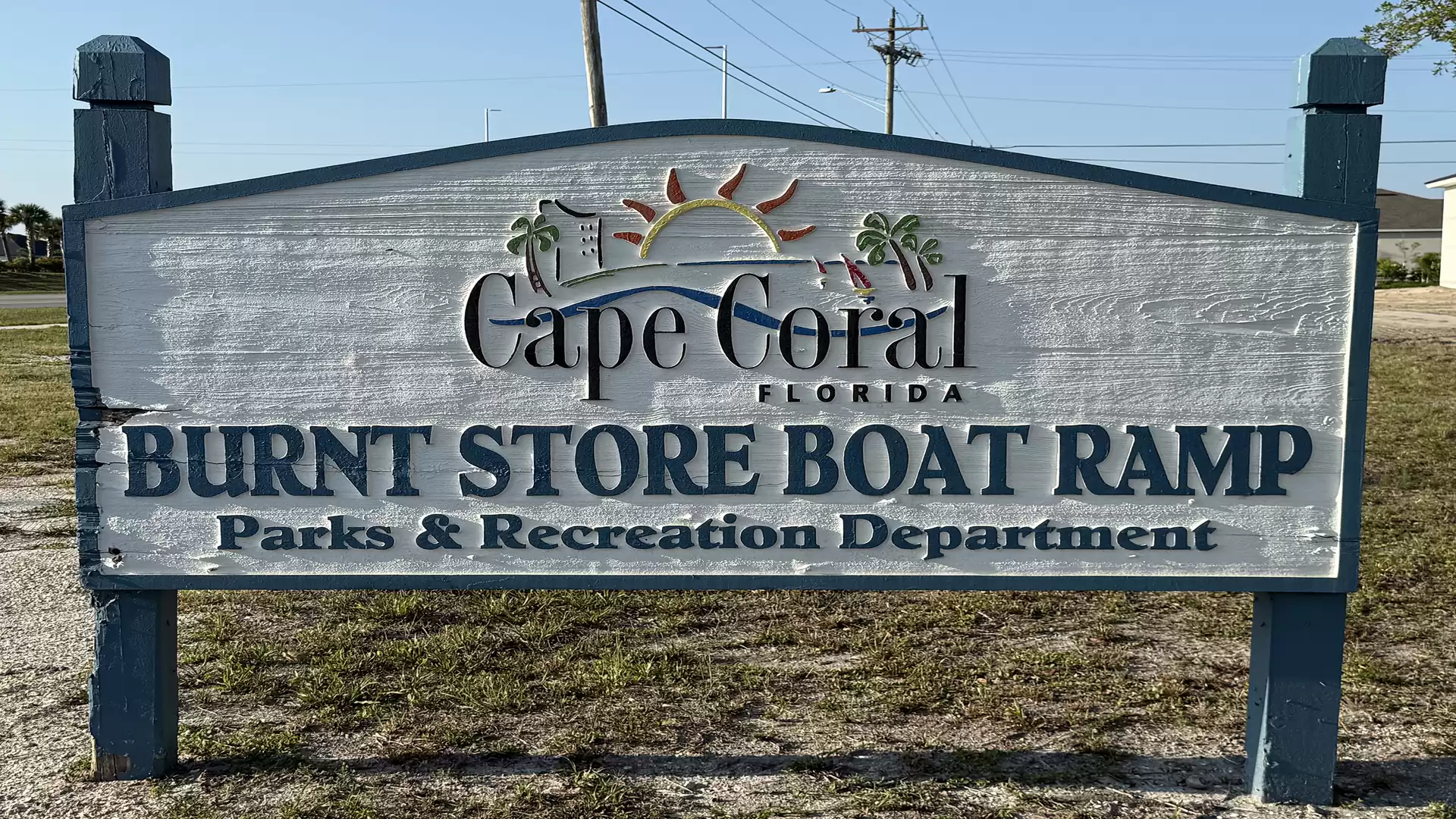 A wooden sign in Cape Coral, Florida, indicating the Burnt Store Boat Ramp, managed by the Parks & Recreation Department.