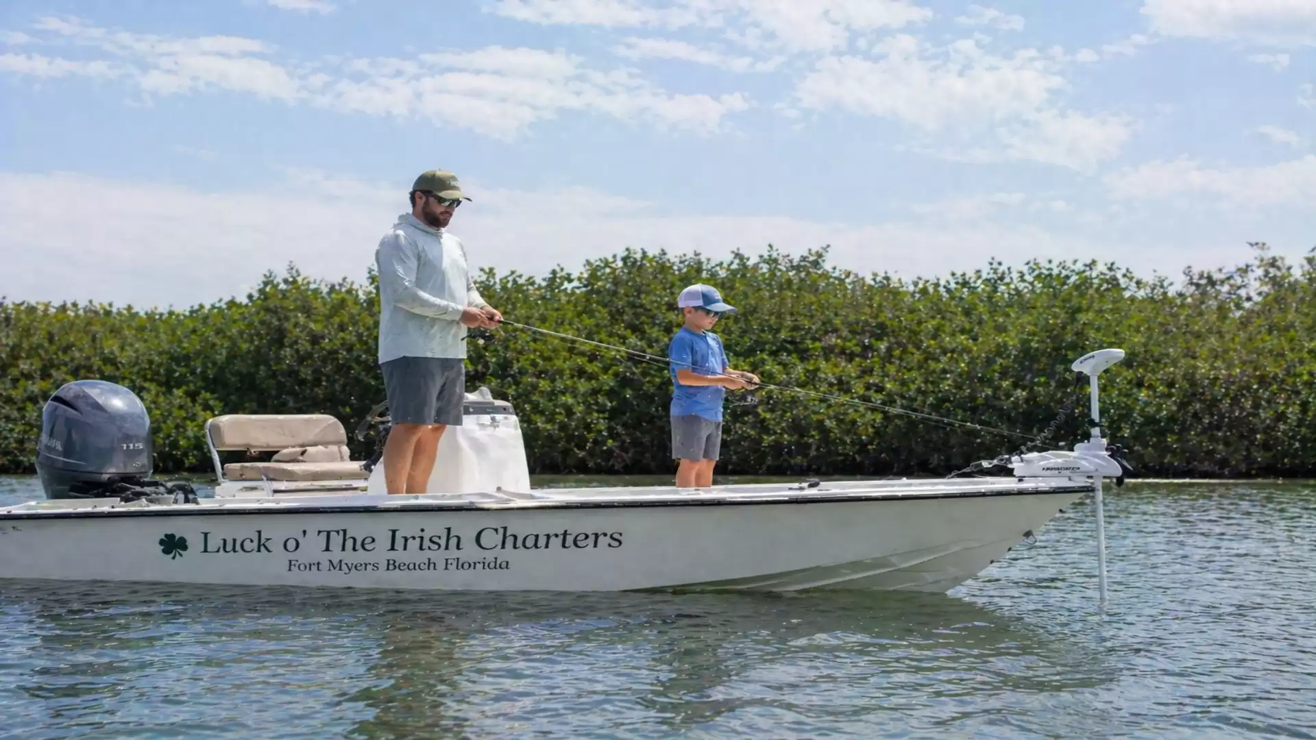 Two people fishing on a boat labeled 'Luck o' The Irish Charters' against a natural backdrop of water and trees.