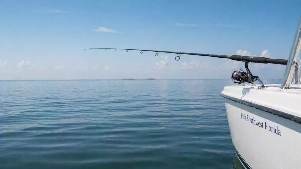 A boat on a calm sea with a fishing rod at the edge of the water.