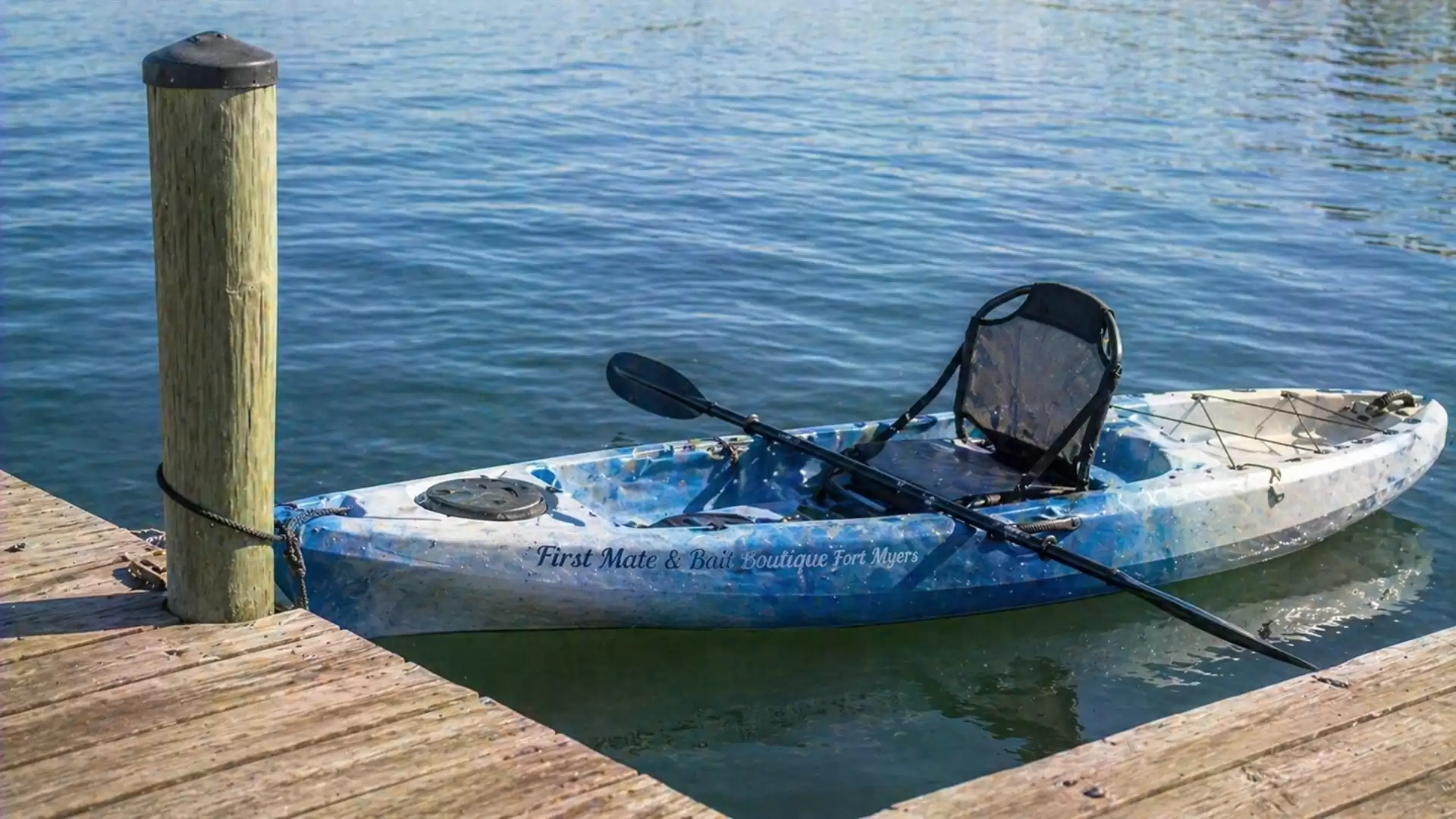A blue kayak moored to a wooden dock in calm water.