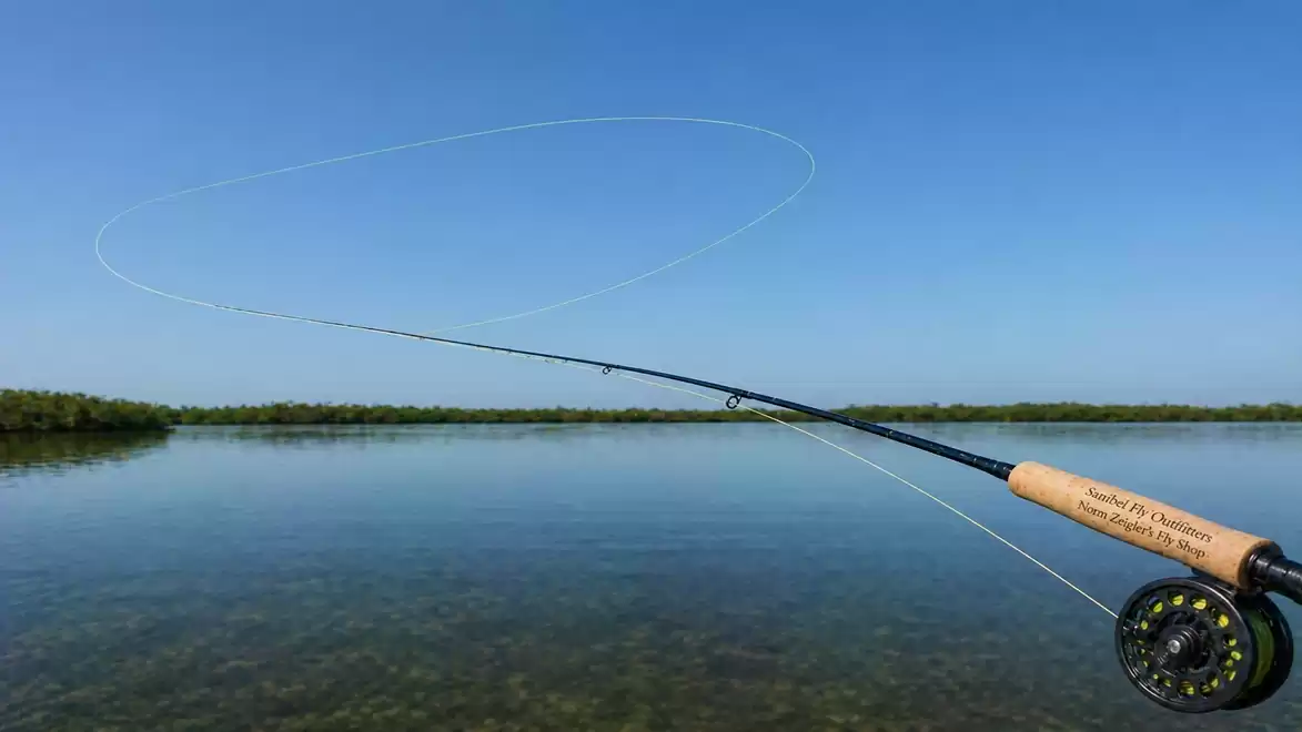 A fishing rod with a fly line over a calm lake under a clear blue sky.
