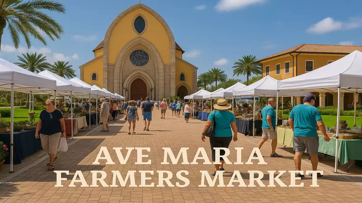 People strolling through a farmers market in front of a church with yellow walls, surrounded by white tents on a sunny day.