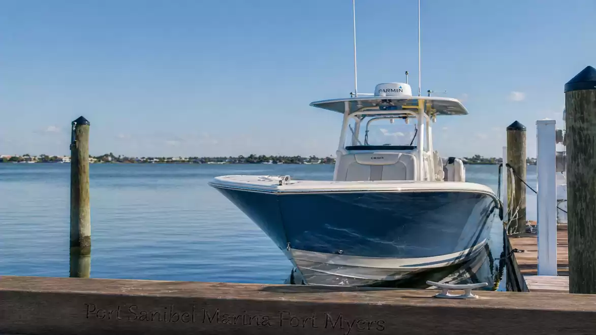 A modern motorboat is moored at a wooden dock. In the background, a calm lake stretches to the horizon.