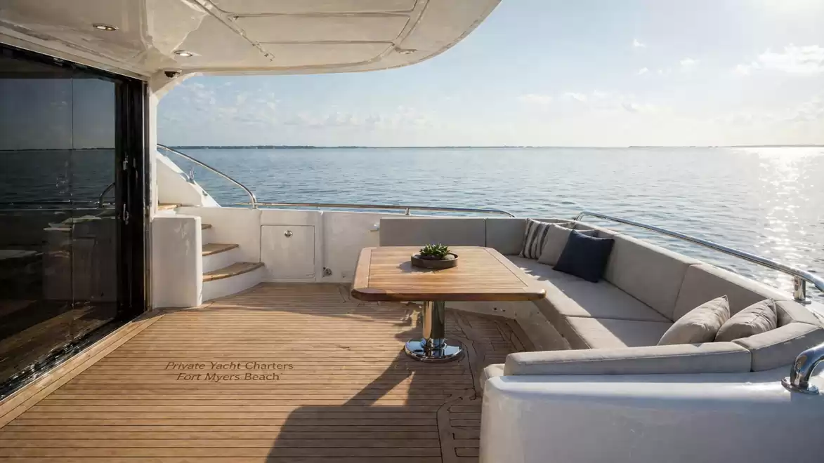 Luxurious yacht deck with a view of the calm ocean, stylish sun loungers and table in the foreground.