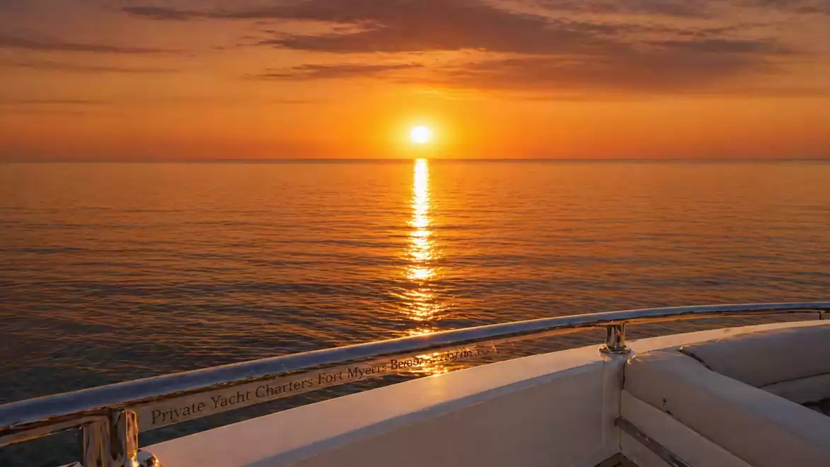 A sunset over the sea, viewed from a boat, with a vibrant orange sky.