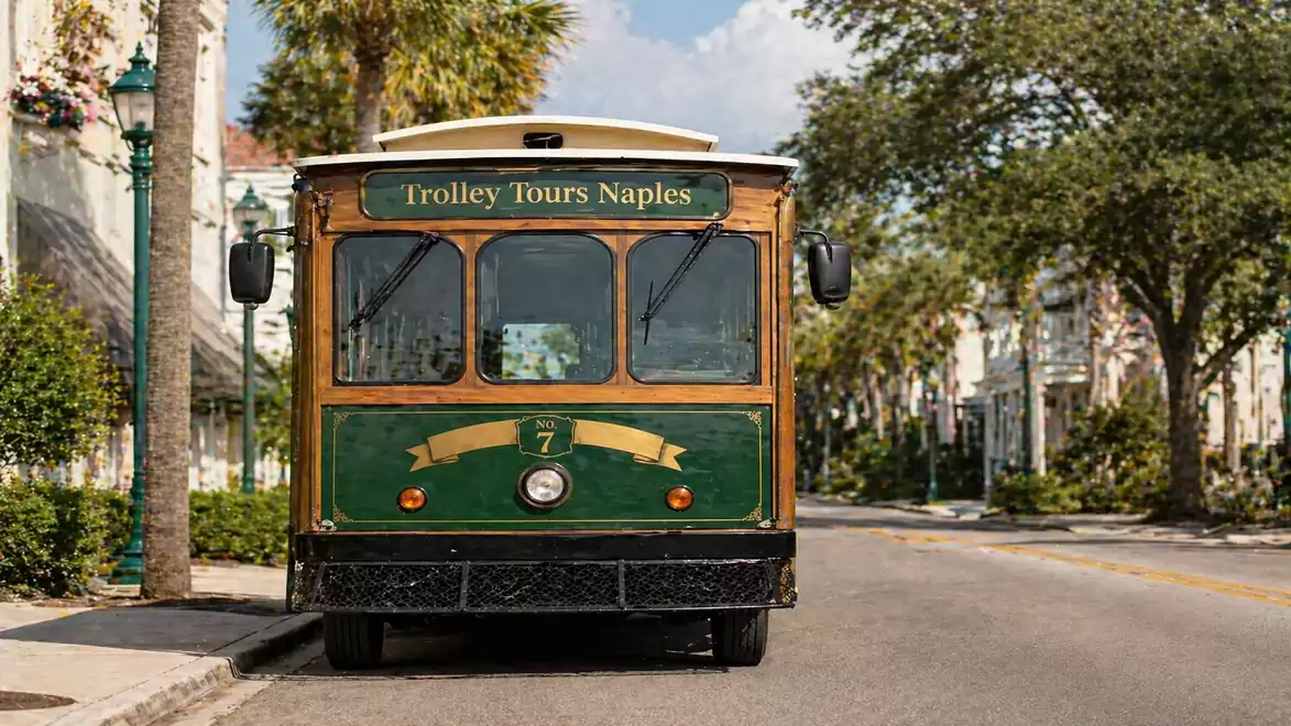 Historic green trolley on a peaceful, sunlit street in Naples.