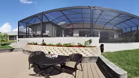 Screened pool lanai with raised flower bed and round table on lower deck