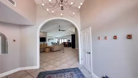 Bright entrance with archway, chandelier, and view into the open-plan living and dining area of a modern vacation home.