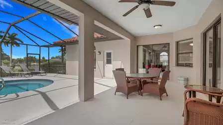 Screened patio with wicker dining set, ceiling fans and view of round pool