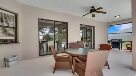 Covered patio with round wicker dining set, ceiling fan and gas grill