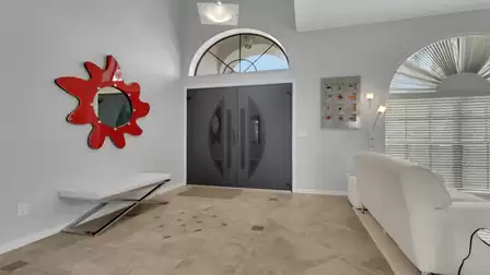 Entry hall with double doors, red splash mirror, white bench and tiled floor