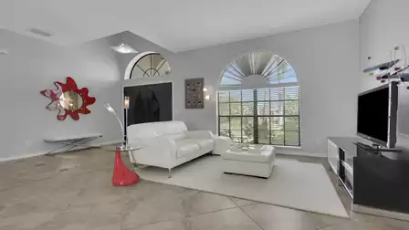 Living area with white sofa, red side table, TV stand and arched window